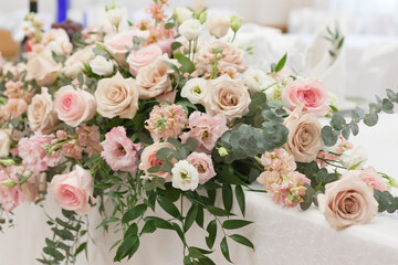 A beautiful floral arrangement in light colors is on the table with a white tablecloth.