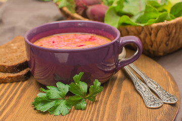 Borsch is a traditional Ukrainian soup. Vegetable soup with sour cream in a ceramic cup on an old wooden surface.