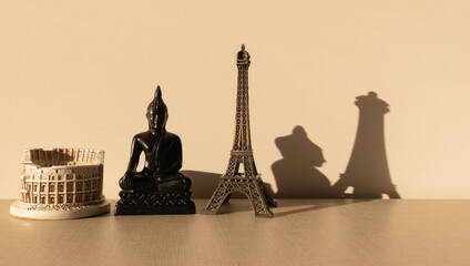Fototapeta na wymiar Coliseum, Buddha and Effeil tower on a wooden table with their shadow