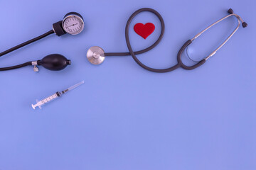 stethoscope, tonometer, syringe, red heart on a blue background. the view from the top