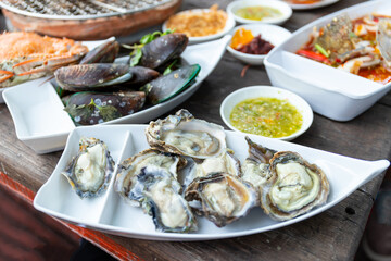 Seafood buffet grill with raw shrimp, shellfish, crab, squid prepared empty, comes in a white plate, looks delicious, delicious, ready to eat, available on a wooden table with a grill.