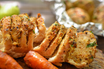 Baked chicken breast. Wooden background. Chicken breast, baked carrots, knife, on a wooden board. Closeup.