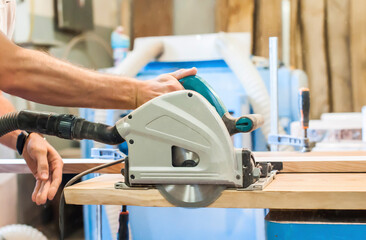 A man works with a circular saw in a carpentry workshop. Center
