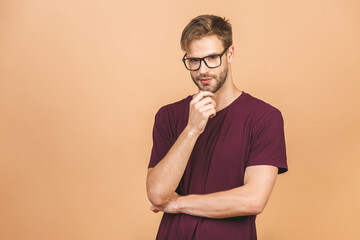 Fototapeta premium Portrait of a handsome man in glasses against beige background with copy space. Smiling guy in casual standing in casual isolated. Successful hispanic man looking at camera.