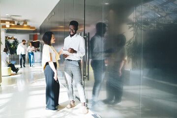 Diverse colleagues standing and moving in modern workplace talking over projects