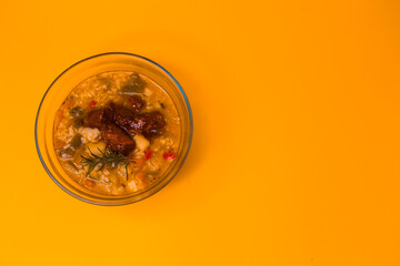 vegan soup in a transparent small glass well on a yellow background on empty