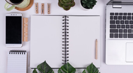 Fototapeta na wymiar Blank notebook with wooden pencil and mock up on office desk with white background. Table for work and write with succulent, coffee cup and phone. Top view.
