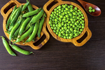 fresh ripe green peas in wooden bowls top view. background with green sweet peas. green polka dots and a copy of the space.