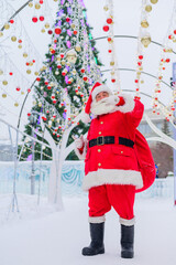 Portrait of an elderly man dressed as santa claus on the background of a christmas tree outdoors.