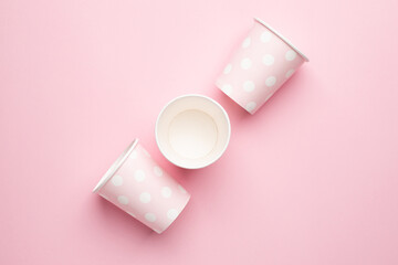 Polka dot disposable paper cups on pink background