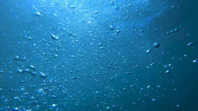 First person view diving in shallow sea water. Ocean floor seabed covered with fine sand. Bubbles floating towards the surface. Concept of drowning and looking up to the surface. Slow motion, point of