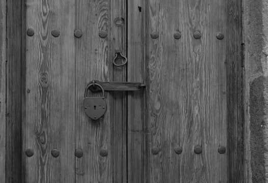 puerta de madera y candado de metal en blanco y negro