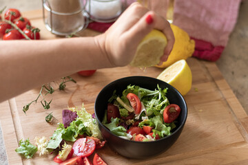 Preparación de ensalada de tomates y verdes, exprimiendo limón