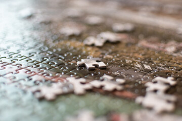 Piece of puzzle on a blurry background, on a living room table. 