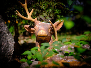 Brown deer ornament statue with a broken horn in the garden