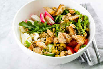 Healthy Salad Bowl. Mozzarella, vegetables, green leaves, green olives, whole grain bread, peanuts