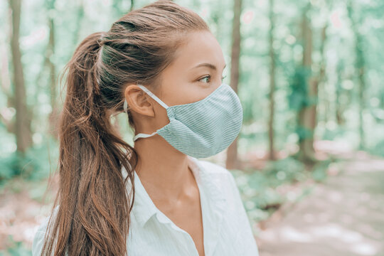 Face mask of cotton fabric are breathable for skin. Asian woman wearing corona virus mouth covering walking outdoors in woods.