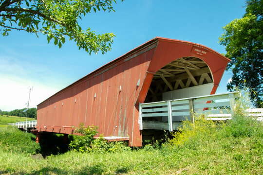 Covered bridge, Madison County, Iowa, Sideways across a ravine with green trees and blue sky, Red planks and white railing  Royalty free stock photo
