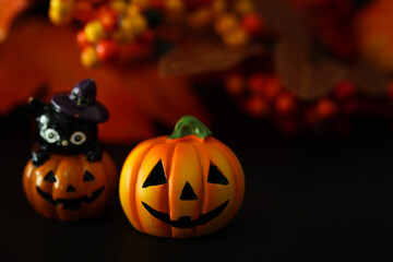 ハロウィンのイメージ素材　黒地にカボチャのクローズアップ　秋の葉と木の実などの背景ぼかし