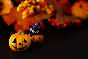 ハロウィンのイメージ素材　黒地にカボチャのクローズアップ　秋の葉と木の実などの背景ぼかし