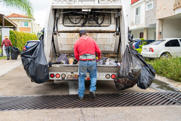 El trabajador de la basura está buscando residuos para reciclar.