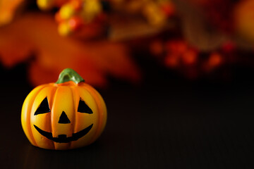 ハロウィンのイメージ素材　黒地にカボチャのクローズアップ　秋の葉と木の実などの背景ぼかし