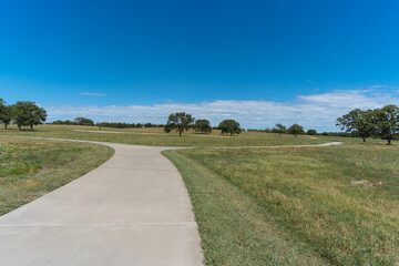 Fototapeta na wymiar A concrete path in a Texas city park on a sunny August day.