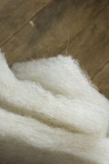Sheep wool material for warming a winter jacket on a background of wooden boards.
