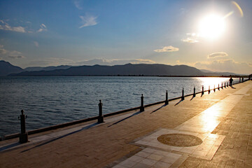 Obraz premium Photo taken into the evening sun as it sinks slowly in the west, casting shadows from the railings on to an ornamental walkway in a Turkish seaside resort.