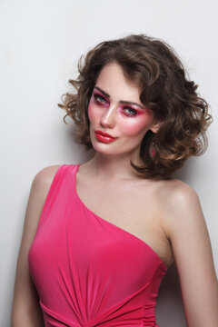 Portrait of young beautiful girl with curly hair and hot pink disco makeup