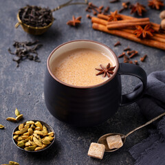 Indian masala tea with milk and spices in mug. Grey background. Close up.