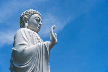 Fototapeta na wymiar Detail of Buddha statue in a Buddhist temple and blue sky background in Danang, Vietnam. Closeup, copy space