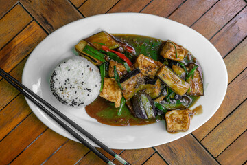 Lightly fried tofu and stew with eggplant, onion, garlic, gravy sauce on plate