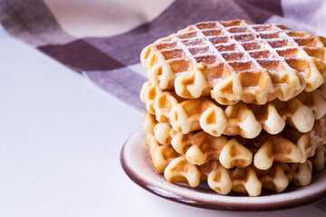 Close-up of stack of round waffles covered with sugar powder.