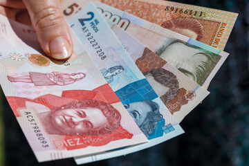 woman is holding Colombian pesos in her hand.