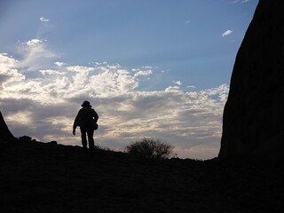 Silhouette of a male tourist hiking uphill in an evening