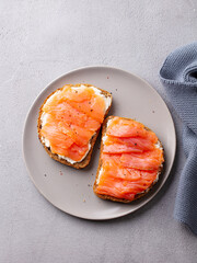 Sandwich, toast with smoked salmon and cream cheese on plate. Grey background. Top view.