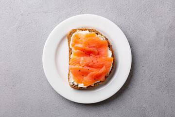 Sandwich, toast with smoked salmon and cream cheese on plate. Grey background. Top view.