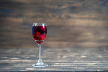Homemade tincture of red cherry. Berry alcoholic drinks concept. Homemade red wine made from ripe cherries in wineglass on wooden background, Ukraine