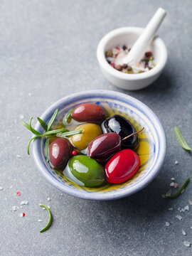 Olives assortment in bowl with oil. Grey background.