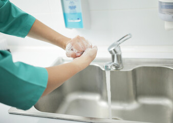 A woman doctor in protective mask washes hands thoroughly in hospital