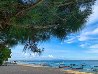 tropical beach with fishing boats againts blue sky at Sanur Beach Bali.