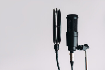 Black condenser microphone on stand with pop filter isolated on gray background with copy space.