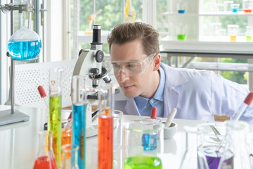 A western scientist man working on test tube to analysis and develop vaccine of covid-19 virus in...