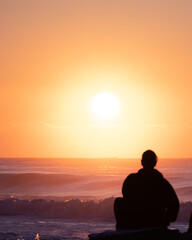 Fototapeta na wymiar silhouette of a man sitting on a rock at sunrise
