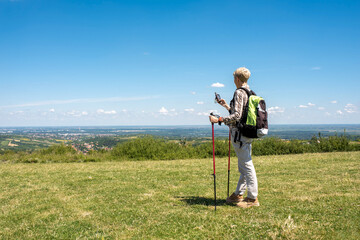 Active senior woman hiker taking a break in the nature while checking coordinates with hand held...