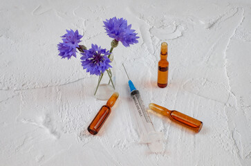 Composition with ampules, medical syringe, and flowers on textured background