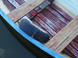 Retro vintage wooden fishing boat detail with a tire in a canal of the lake Balaton, Hungary