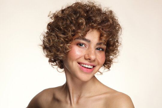 Portrait of smiling beautiful young freckled girl with curly hair