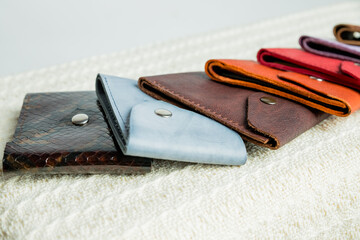 Colorful leather wallets.Leather handmade wallets of different forms lying on a beige textile background. Selling point leather goods.